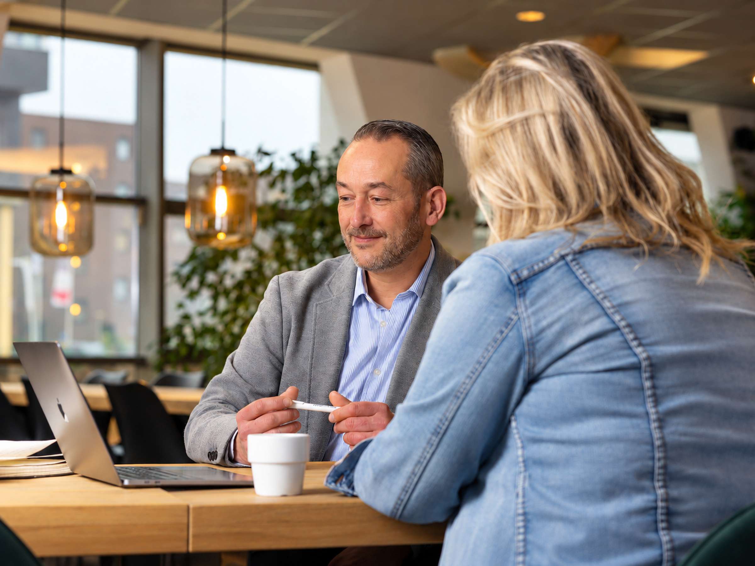 Serge in overleg met een klant aan tafel, met zijn laptop open