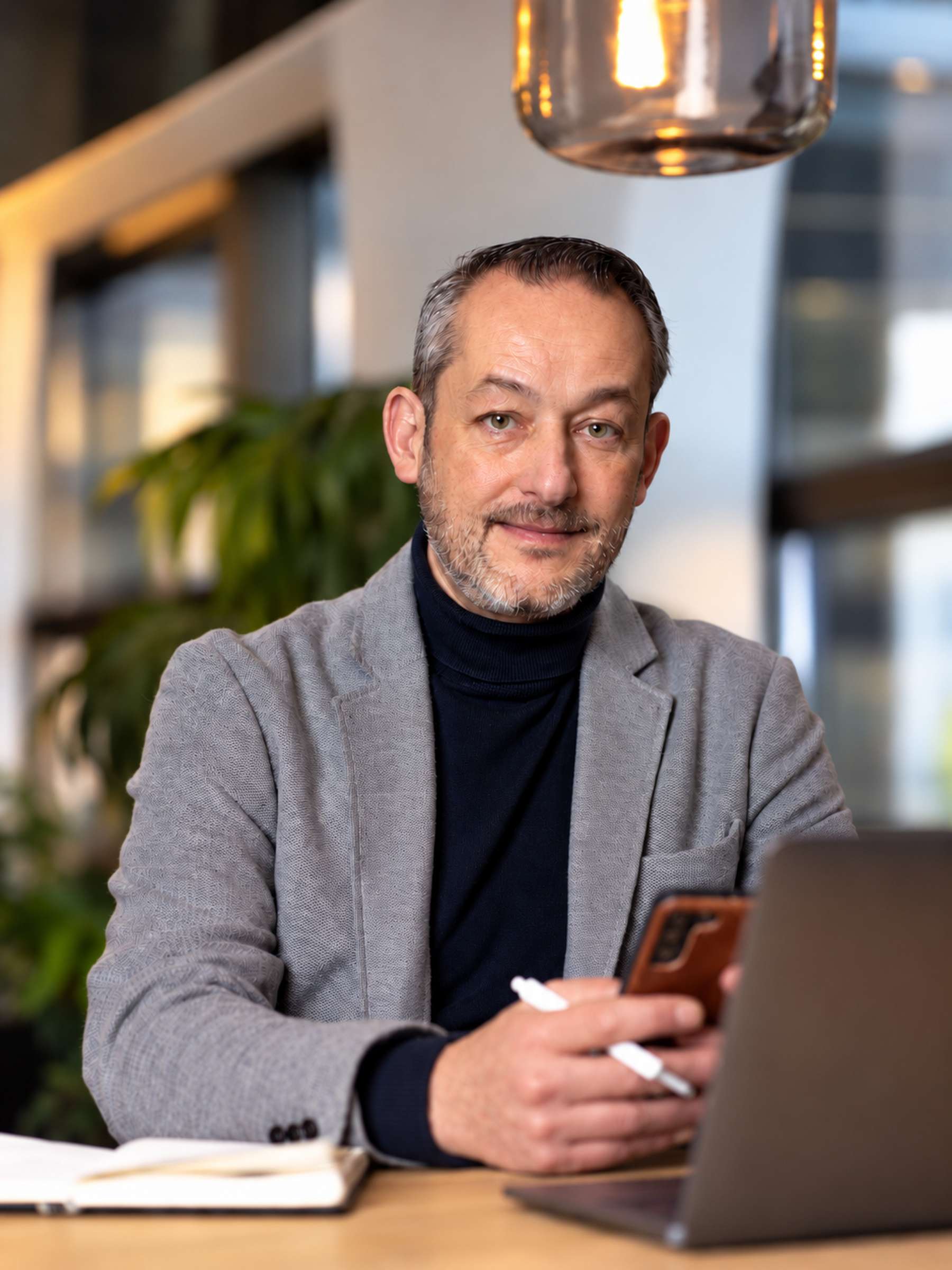 Serge aan tafel met zijn laptop en smartphone
