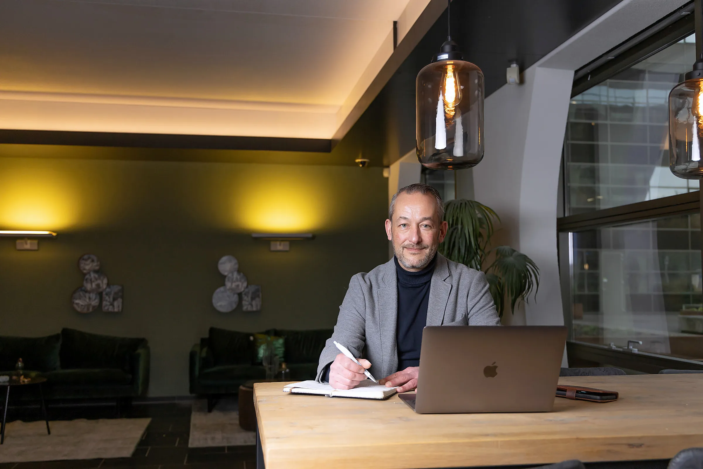 Serge werkt aan tafel op zijn laptop en maakt notities